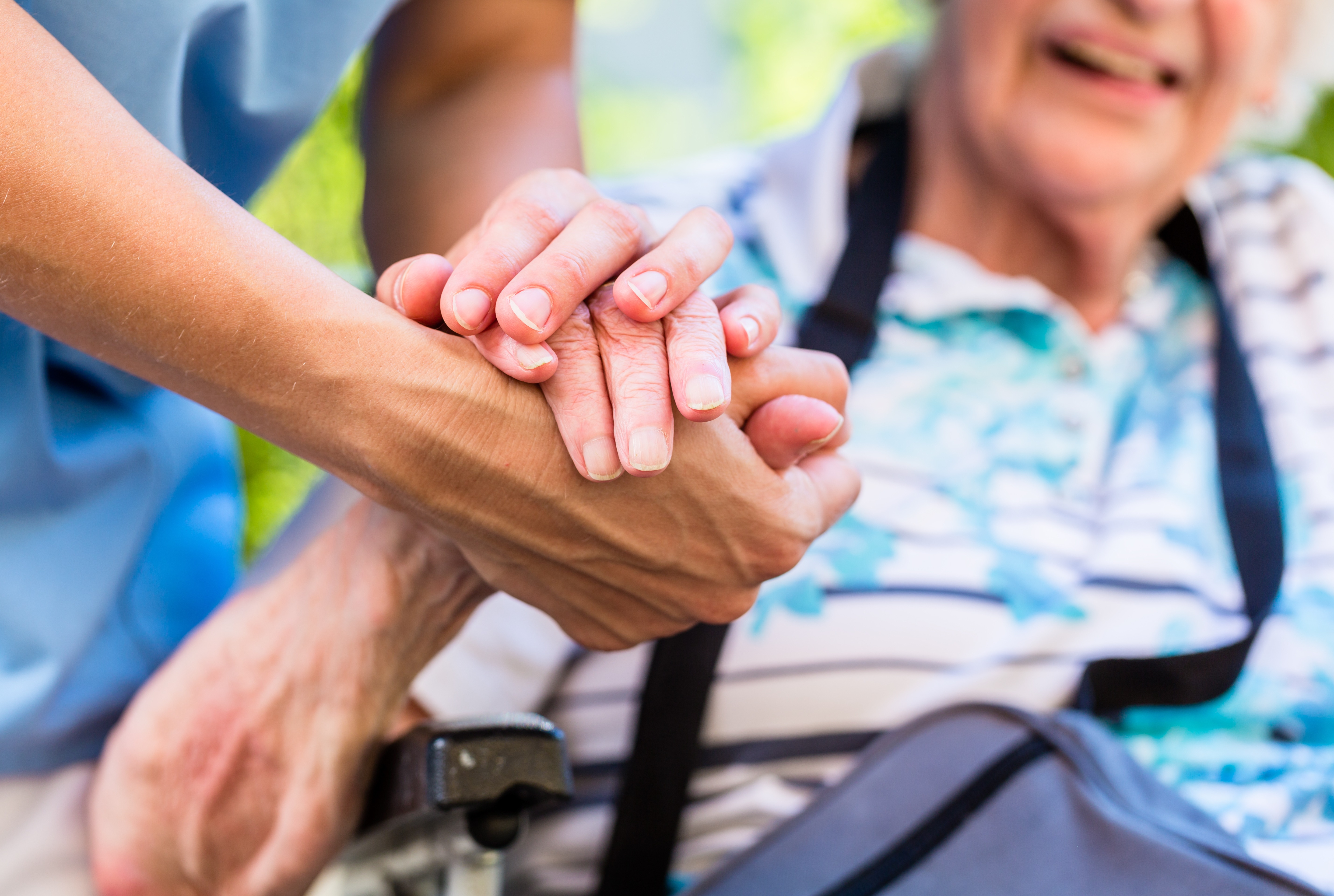 Krankenschwester tröstet ältere Frau und hält ihre Hand